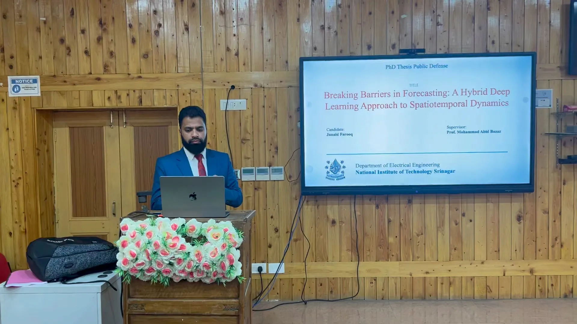 Junaid Farooq at the lectern with the title slide of his thesis